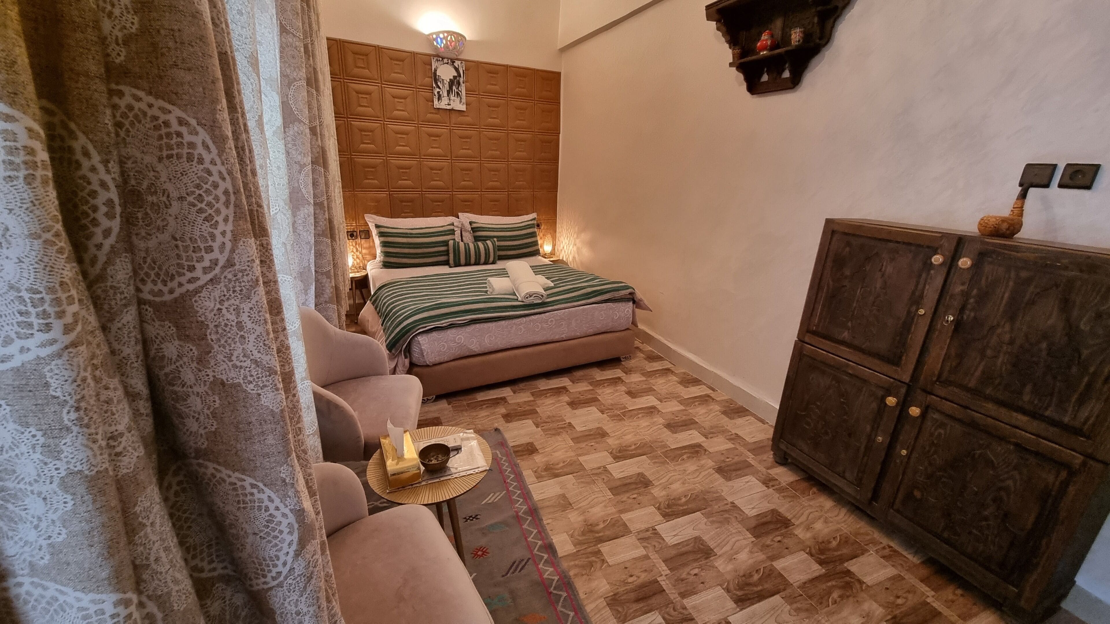 A bedroom with a bed, a sofa, a small table, and a cabinet.