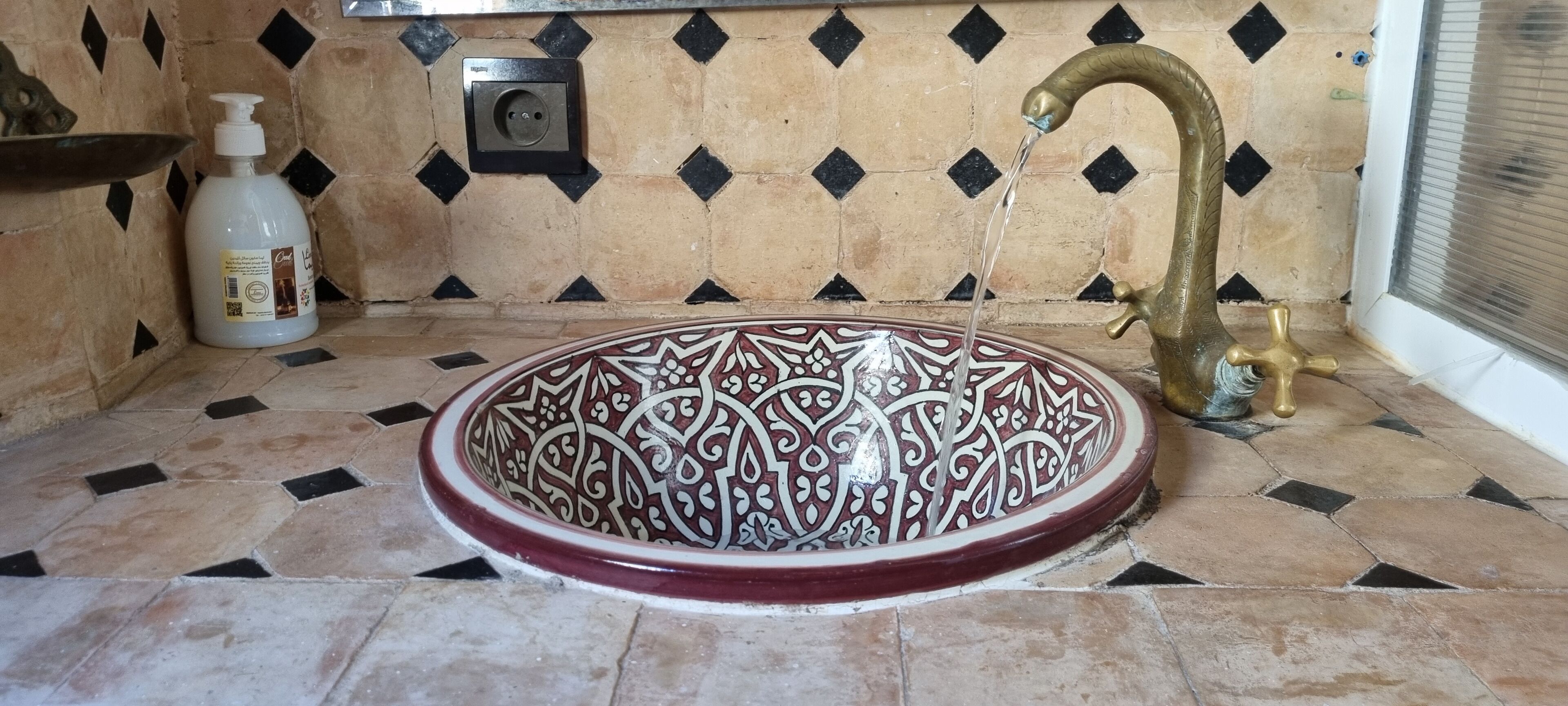 A bathroom with a decorative sink, a faucet, and a bottle of hand soap.