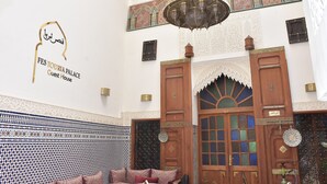 A traditional Moroccan interior with a sign for FES Touria Palace Guest House, ornate wooden doors, and patterned tile work. - Fes Touria Palace (Fes)