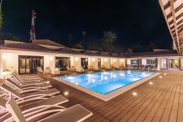 A swimming pool with lounge chairs and a covered deck area. - Hakuna Maldives (Thoddoo)