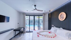 Et moderne hotelværelse med en stor seng, et skrivebord og udsigt til en swimmingpool.