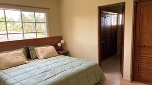 Une chambre à coucher avec un lit, une table de chevet, une fenêtre et une porte.