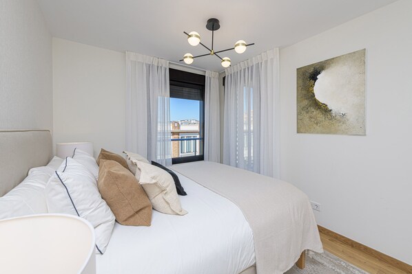 Ein Schlafzimmer mit Bett, einem Fenster mit Vorhängen, einer Deckenleuchte und einem Wandbild.