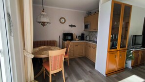 Cocina compacta con armarios de madera, microondas y televisor.