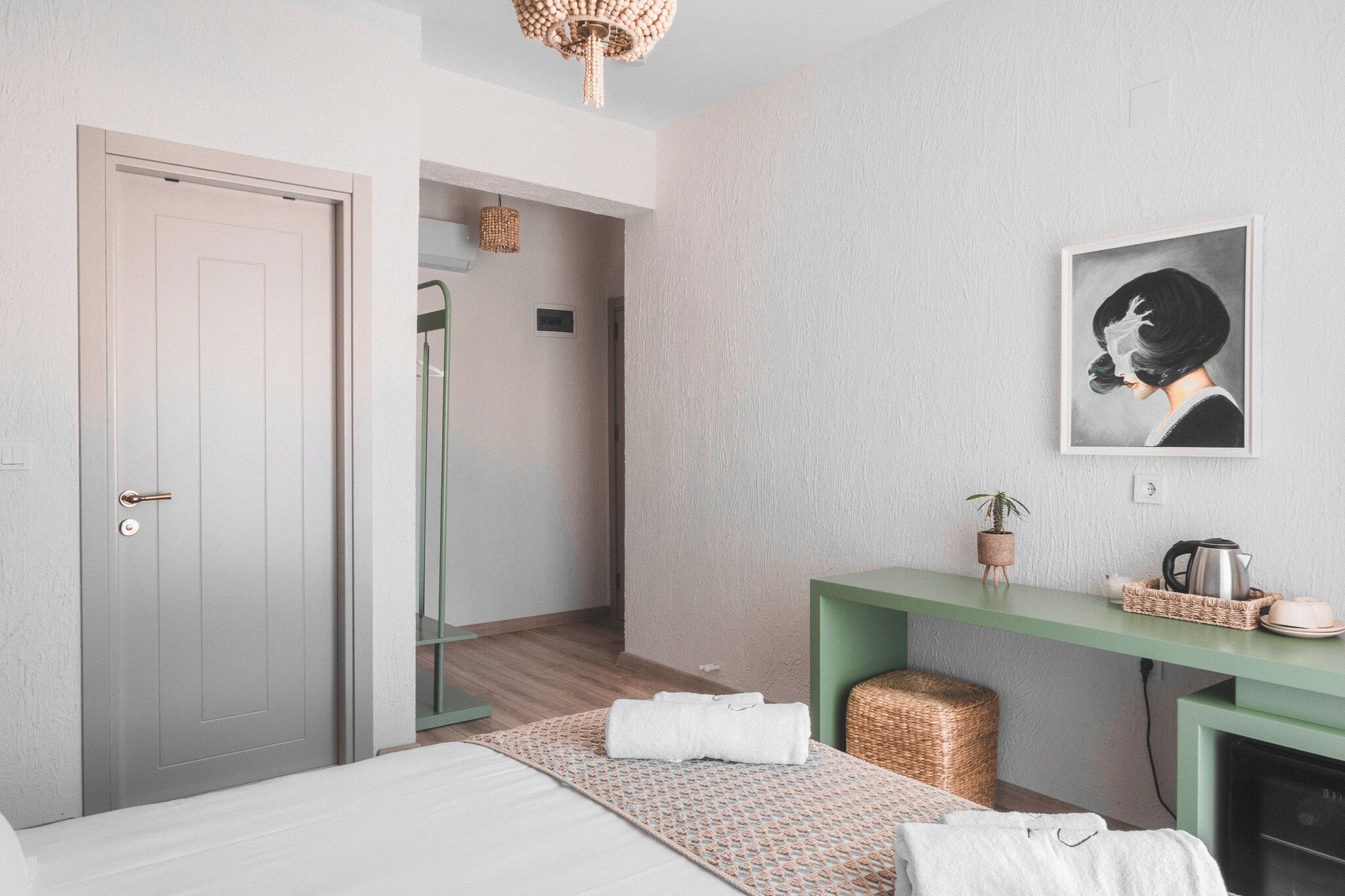 A modern bedroom with a bed, a green console table, a framed artwork, and a shower area.