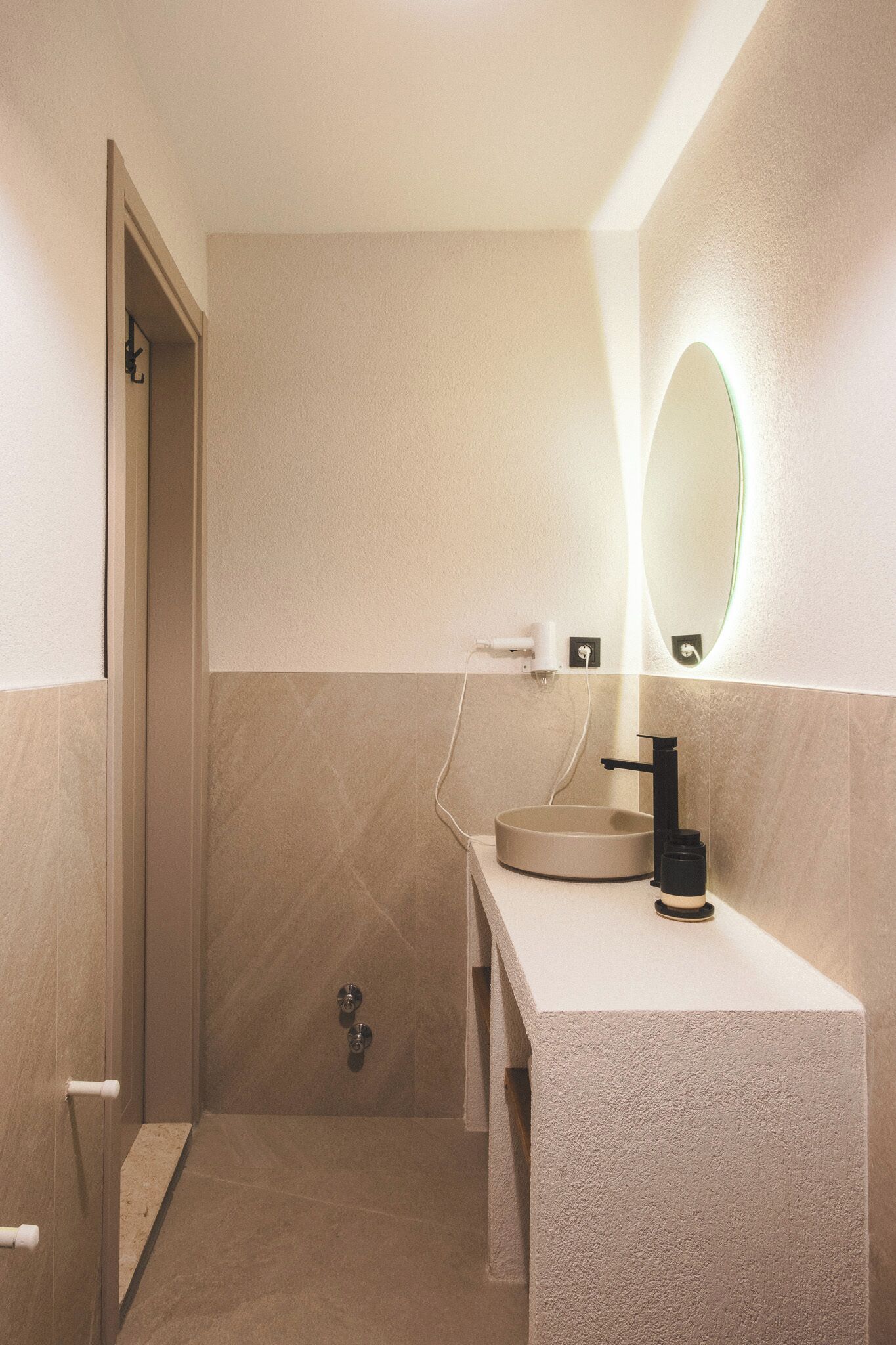 Ein modernes Badezimmer mit einem runden Waschbecken, einem Spiegel und einer Dusche.
