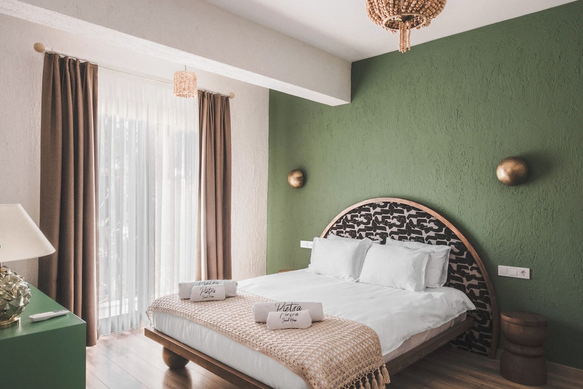 A bedroom with a bed, curtains, a lamp, and a green wall.