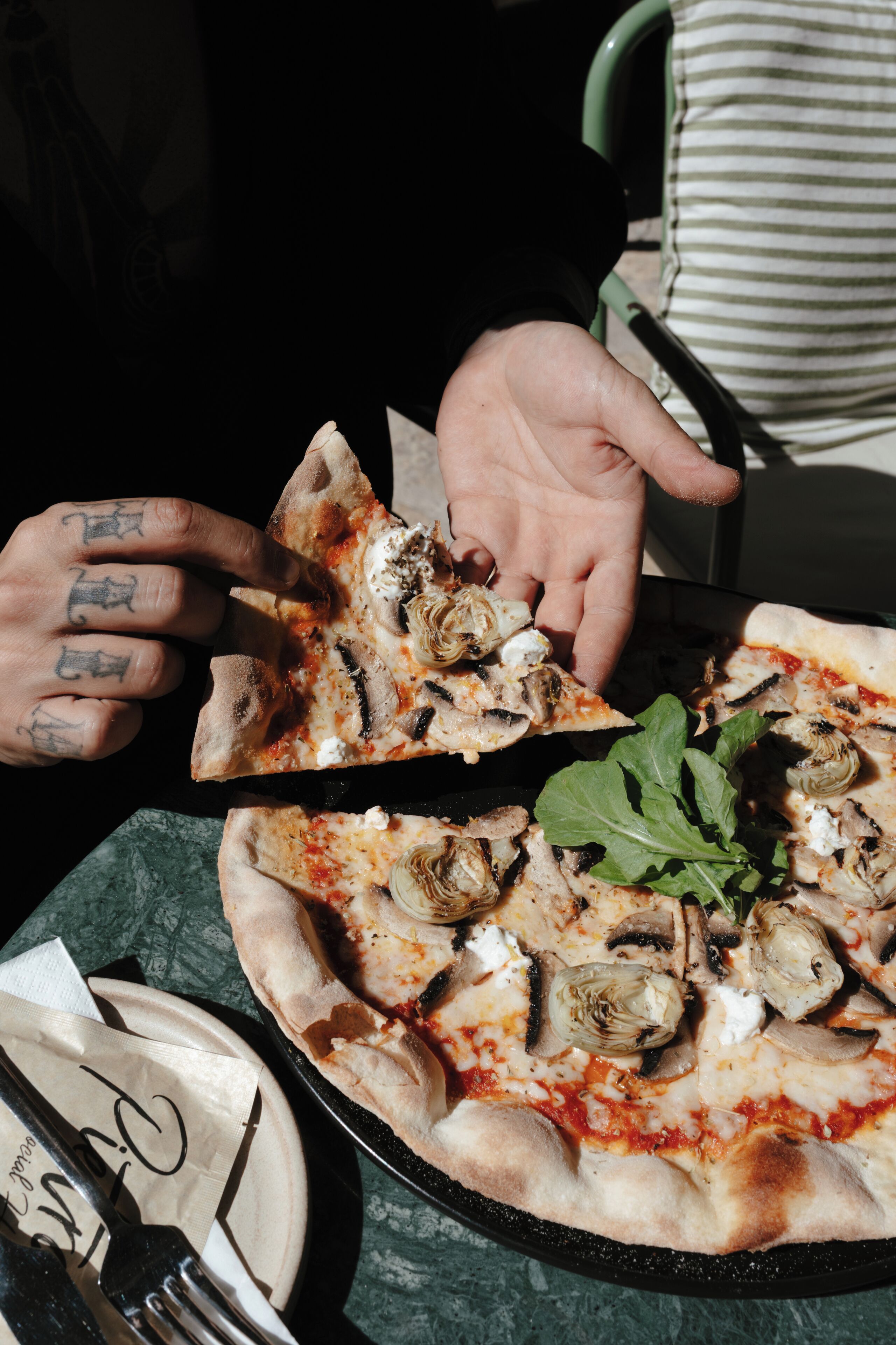 A pizza with artichokes and a basil leaf on a table.