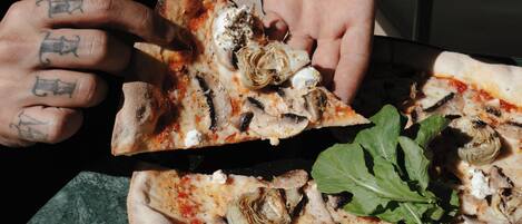 A pizza with artichokes and a basil leaf on a table.