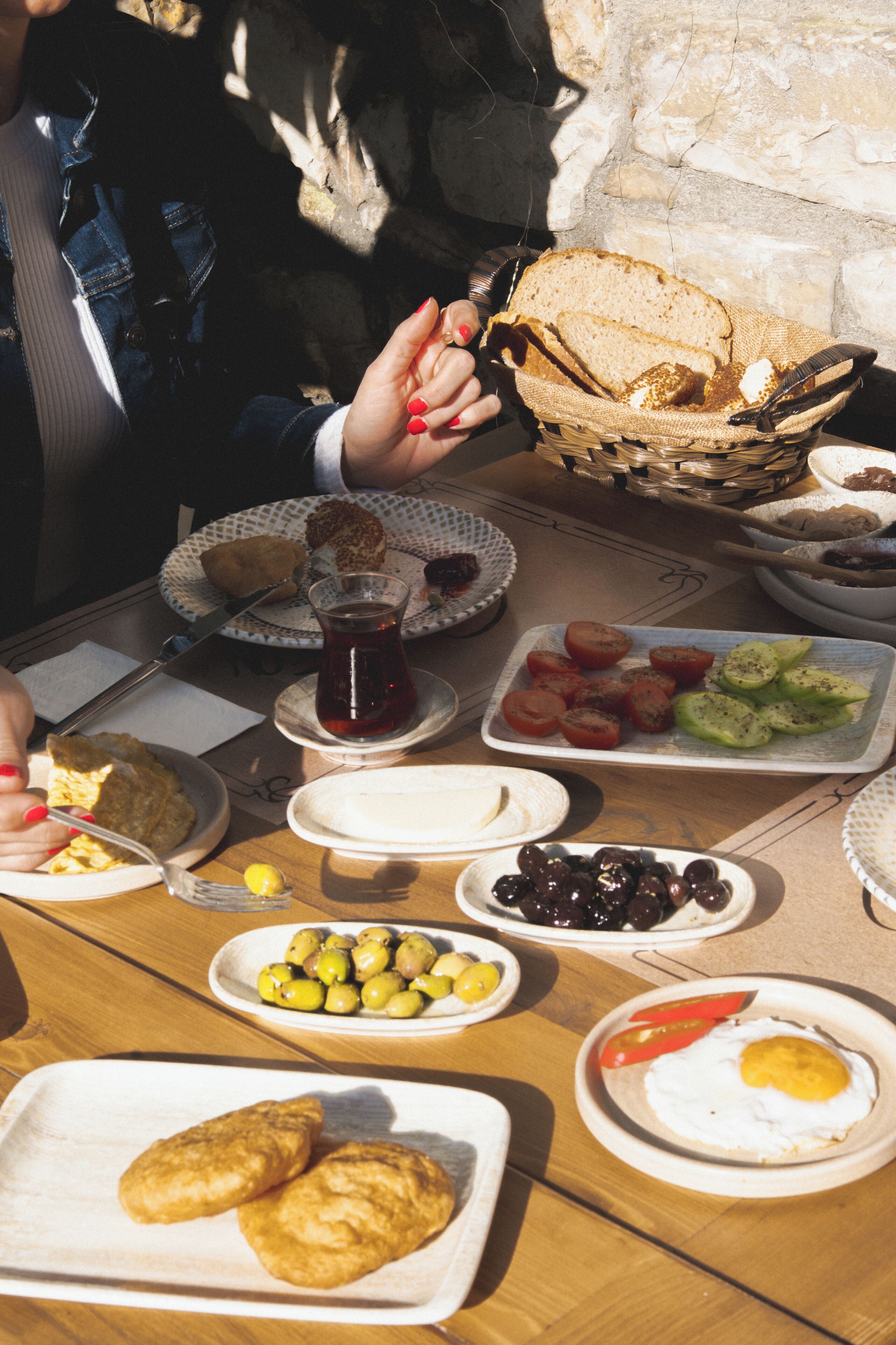 Et morgenbord med forskelligt mad, herunder brød, æg, oliven og tomater.