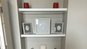 A white shelving unit with three levels, each holding decorative items.
