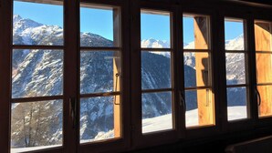 Ein Zimmer mit mehreren Fenstern und Blick auf schneebedeckte Berge.
