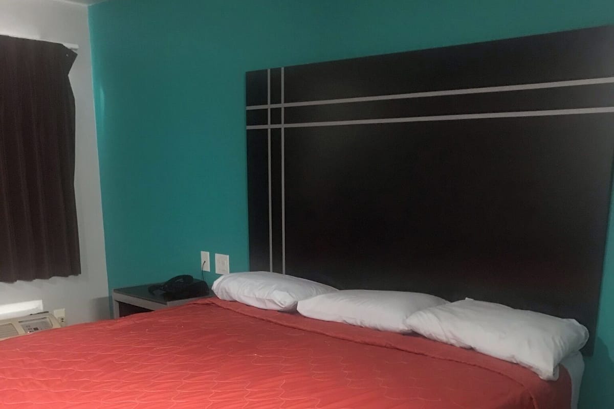 A bedroom with a bed, a nightstand, and a wall-mounted telephone.