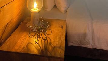 Cabecera de madera, lámpara de noche y cama con ropa blanca.