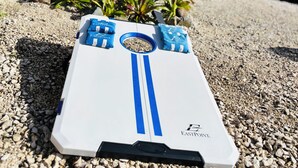 A white object with blue stripes and the text "EASTPOINT" on a gravel surface.