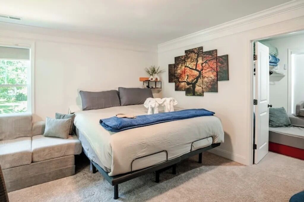 A bedroom with a bed, a sofa, and a painting on the wall.