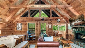 A log cabin interior with a wooden ceiling, a fireplace, a sofa, a bench, and a dining area. - Romantic private cabin near Pigeon Forge - Hot Tub, Fireplace, Views!!! (Pigeon Forge)