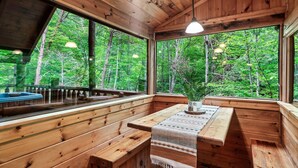 A wooden cabin with large windows, a bench, and a table with a vase. - Romantic private cabin near Pigeon Forge - Hot Tub, Fireplace, Views!!! (Pigeon Forge)