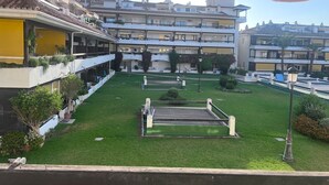 Une cour avec une pelouse verdoyante, une petite piscine et une clôture blanche.