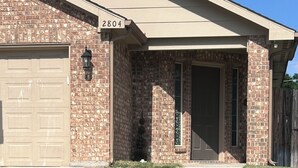 A residential house with a brick facade, a garage, and a well-maintained lawn.