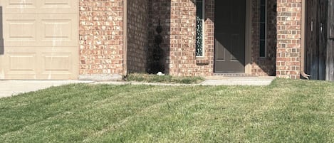 A residential house with a brick facade, a garage, and a well-maintained lawn.