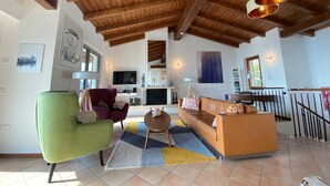 A spacious living room with a wooden ceiling, a green armchair, a red sofa, and a brown couch. - Soothing villa with with private pool, seasonally heated; pet friendly (Villanuova sul Clisi)