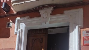 A wooden door with a brass knocker, set in a white frame with decorative molding. - Suite El Califa (Córdoba)