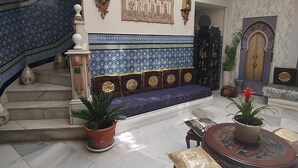 A spacious lobby with a grand staircase, a seating area with a patterned bench, and a decorative wall. - Suite El Califa (Córdoba)