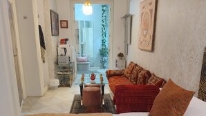 A hotel room with a bed, a sofa, a coffee table, and a view of the outside. - Suite El Califa (Córdoba)