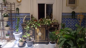 A room with a tiled floor, a ceiling with white beams, a door, and a wall with a blue and white patterned tile border. - Suite El Califa (Córdoba)