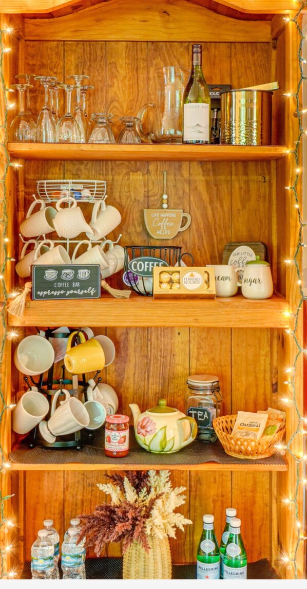 Una estantería de madera con diversos artículos de café y té, como tazas, una tetera y tarros.