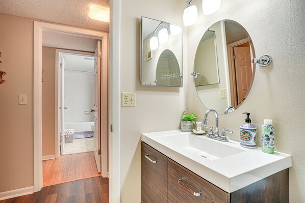 A bathroom with a white sink, a mirror, and a potted plant.