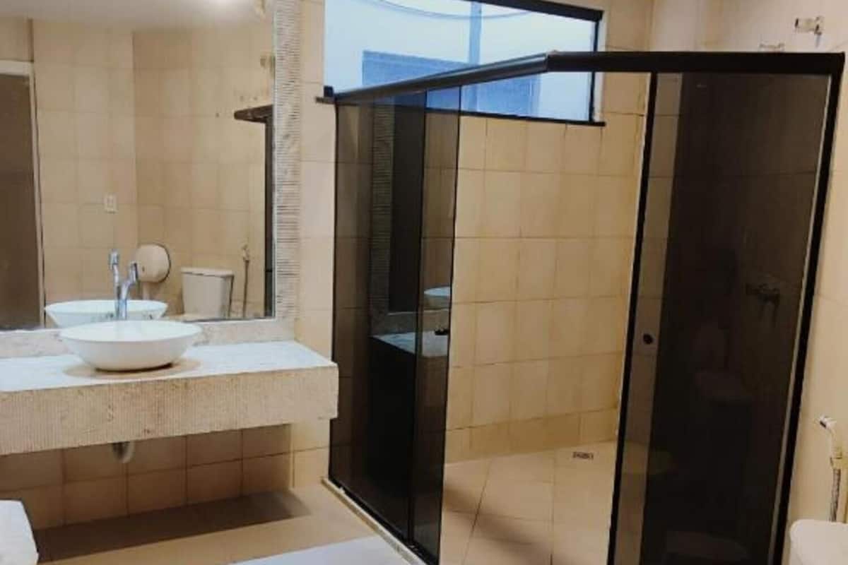 A modern bathroom with a glass shower enclosure, a large mirror, and a white toilet.