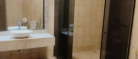Une salle de bain moderne avec une douche à parois de verre, un grand miroir et des toilettes blanches.