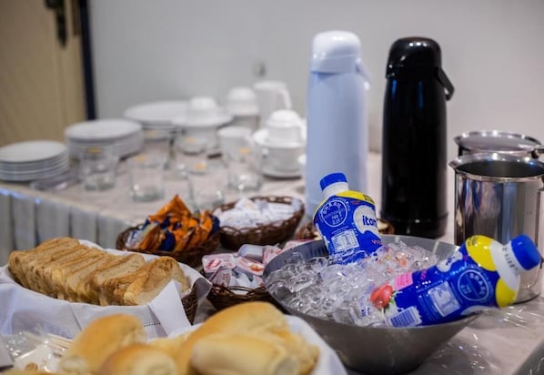 A buffet table with various food items, including bread, ice, and bottled beverages. - Hotel veneza (Itabuna)