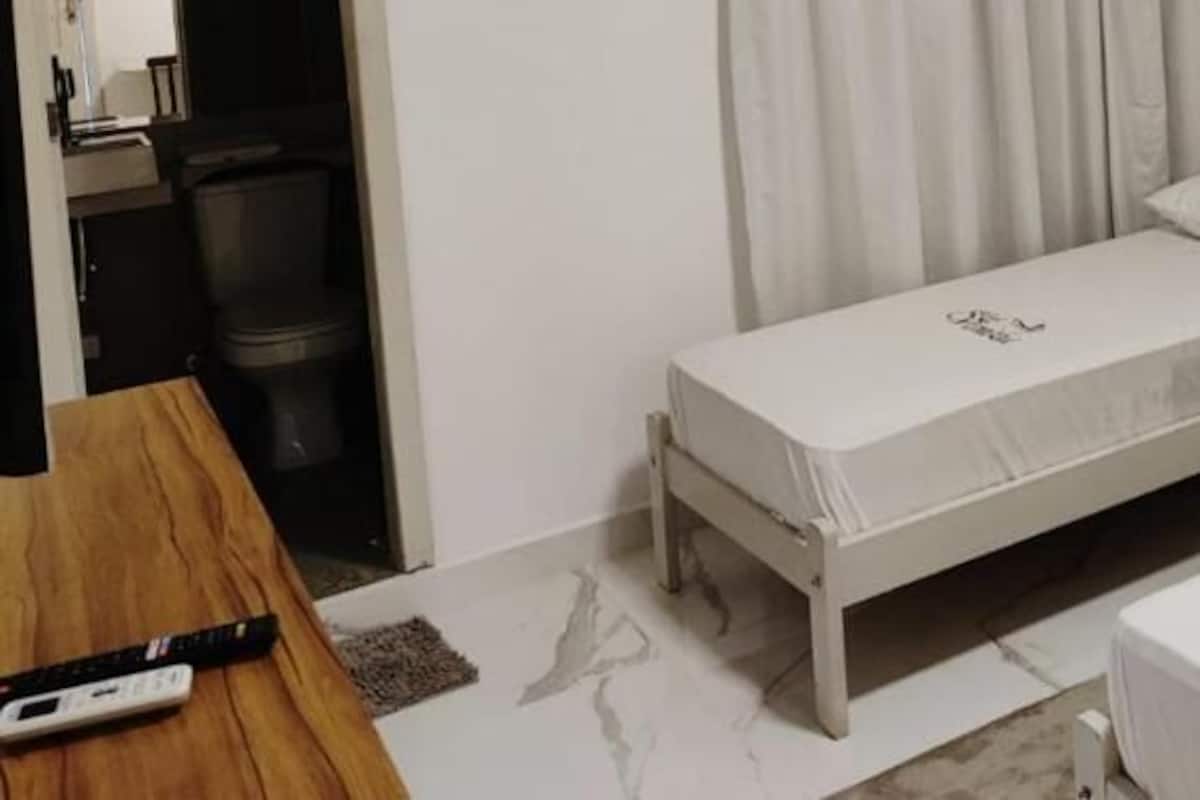 A small hotel room with two single beds, a wooden desk, a telephone, and a small table.