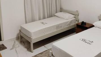Una habitación de hotel pequeña con dos camas individuales, un escritorio de madera, un teléfono y una mesita.