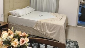 Ένα μικρό, καλαίσθητο υπνοδωμάτιο με ένα μονό κρεβάτι, ένα κομοδίνο, μια καρέκλα και ένα τραπέζι με ένα βάζο γεμάτο λουλούδια.