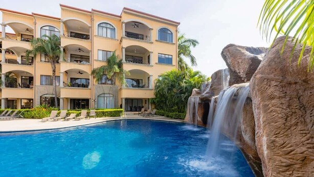 Ein mehrstöckiges Hotel mit Schwimmbad und Wasserfall.