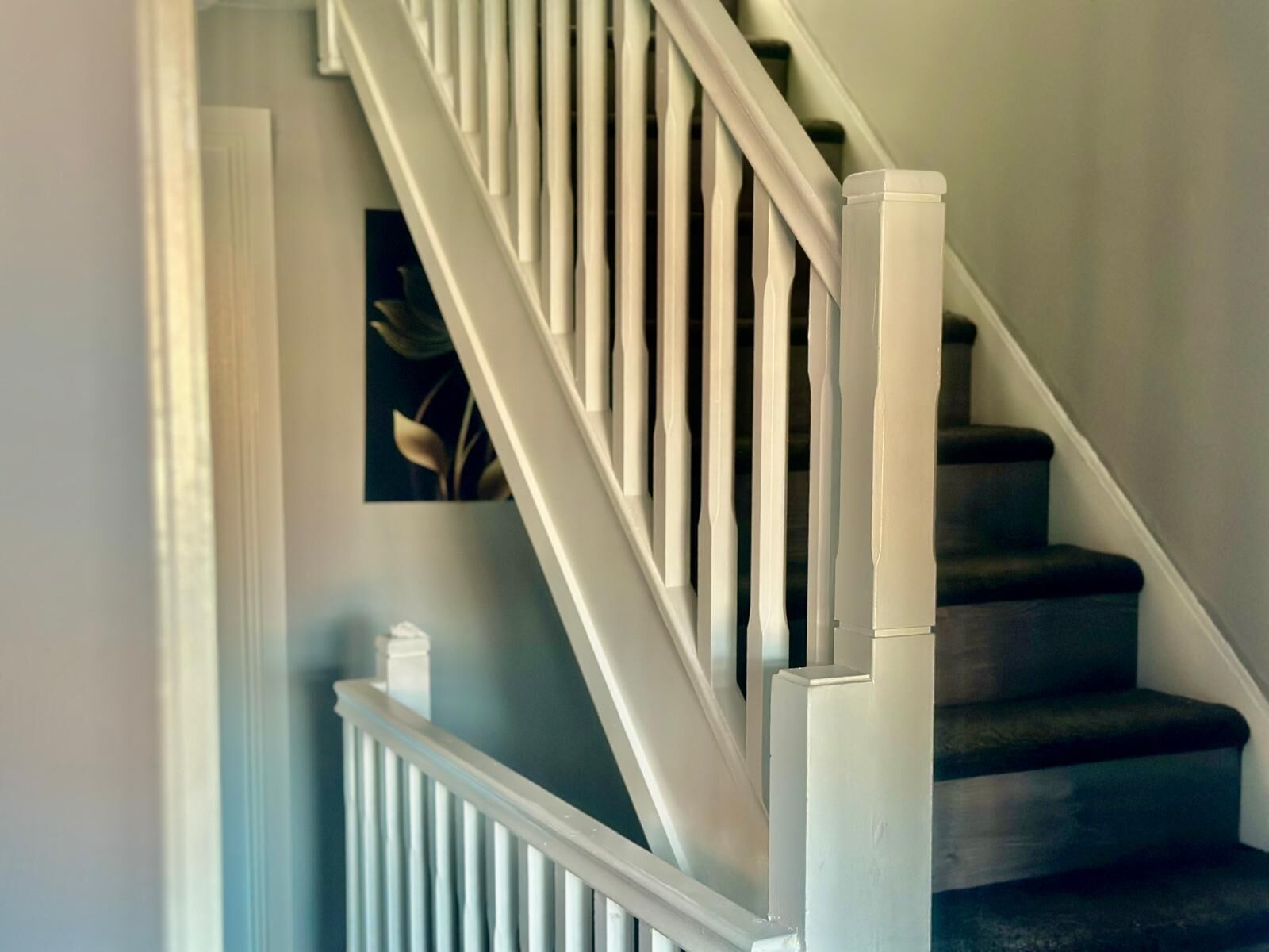 Un escalier avec des rampes blanches et des marches sombres.