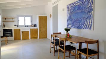 Eine geräumige Küche mit Holzschränken, ein Essbereich mit einem Holztisch und Stühlen sowie ein großes abstraktes Gemälde an der Wand.