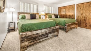 A bedroom with two wooden beds, white walls, and a large wardrobe.