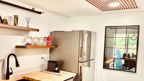 Una cucina moderna con un frigorifero in acciaio inossidabile, un rubinetto nero, piani di lavoro in legno e una finestra vista all'esterno.