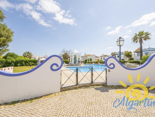 A pool area with a gate, a sun logo, and a paved walkway.