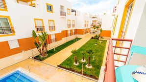 Un patio de hotel con piscina, césped verde y palmeras.