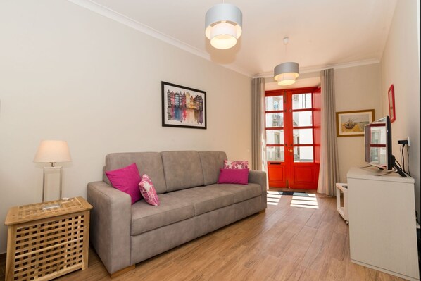 Relax in this stylish living room with a sofa, side table, and TV.