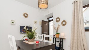 A dining area with a dark wooden table, white chairs, and a potted plant. - Florinda Townhouse in Historical Center (Tavira)