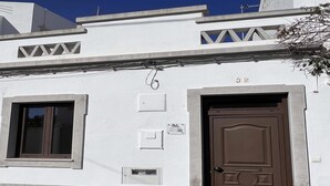 A building with a brown door, a window, and a small sign on the wall. - Florinda Townhouse in Historical Center (Tavira)