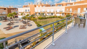 Pátio de hotel com área de estar externa, piscina e vista dos edifícios ao redor.