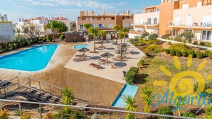 Un resort con una amplia piscina, tumbonas y una terraza de madera.